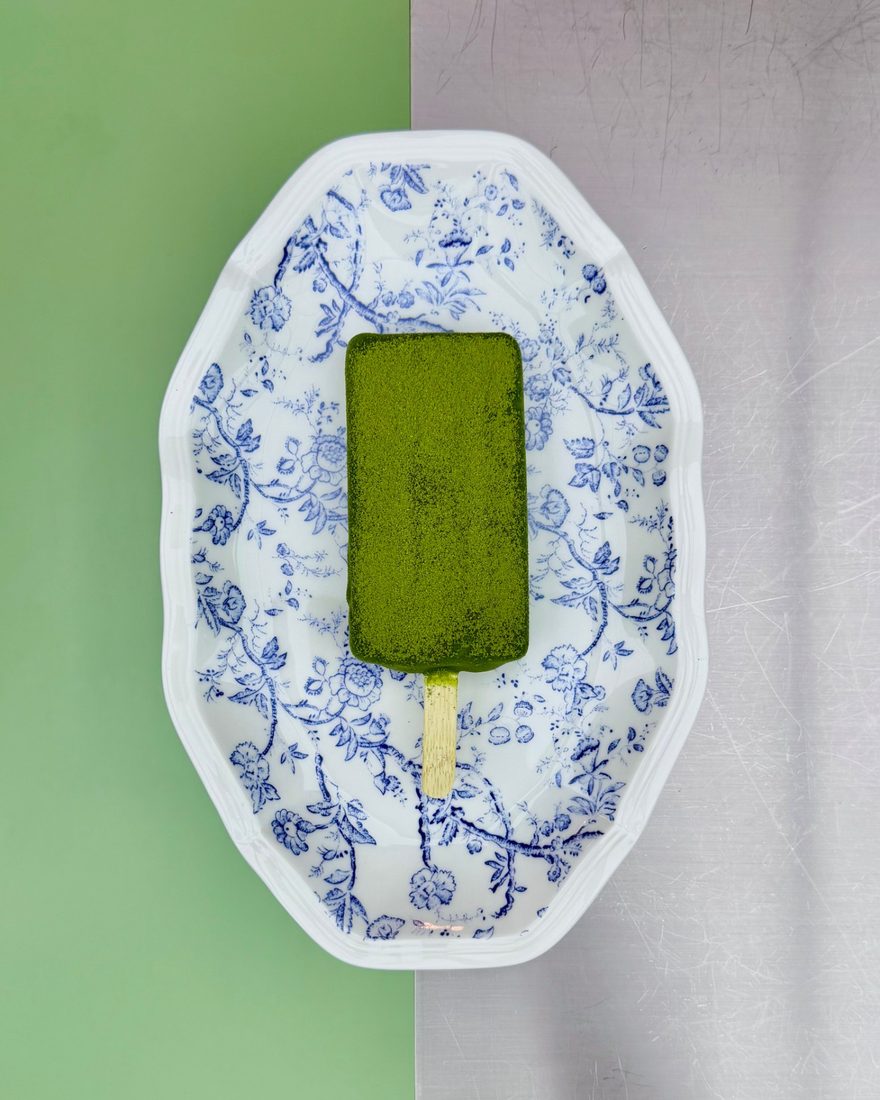 The matcha "Magnum" at [CUISINE] Bangkok, a matcha-dusted ice cream bar on a blue floral plate