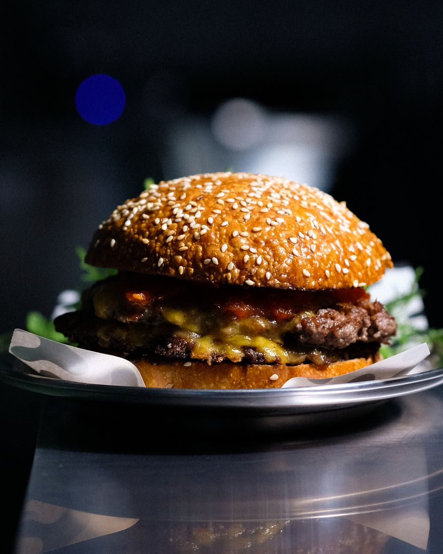 The smash cheeseburger at [CUISINE] Bangkok, two crisp wagyu patties with melted cheddar in a sesame bun